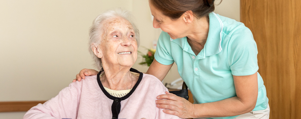 Elderly woman being cared for by a caregiver.