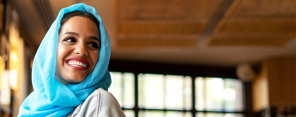 Woman with a headscarf smiling and looking over her left shoulder.