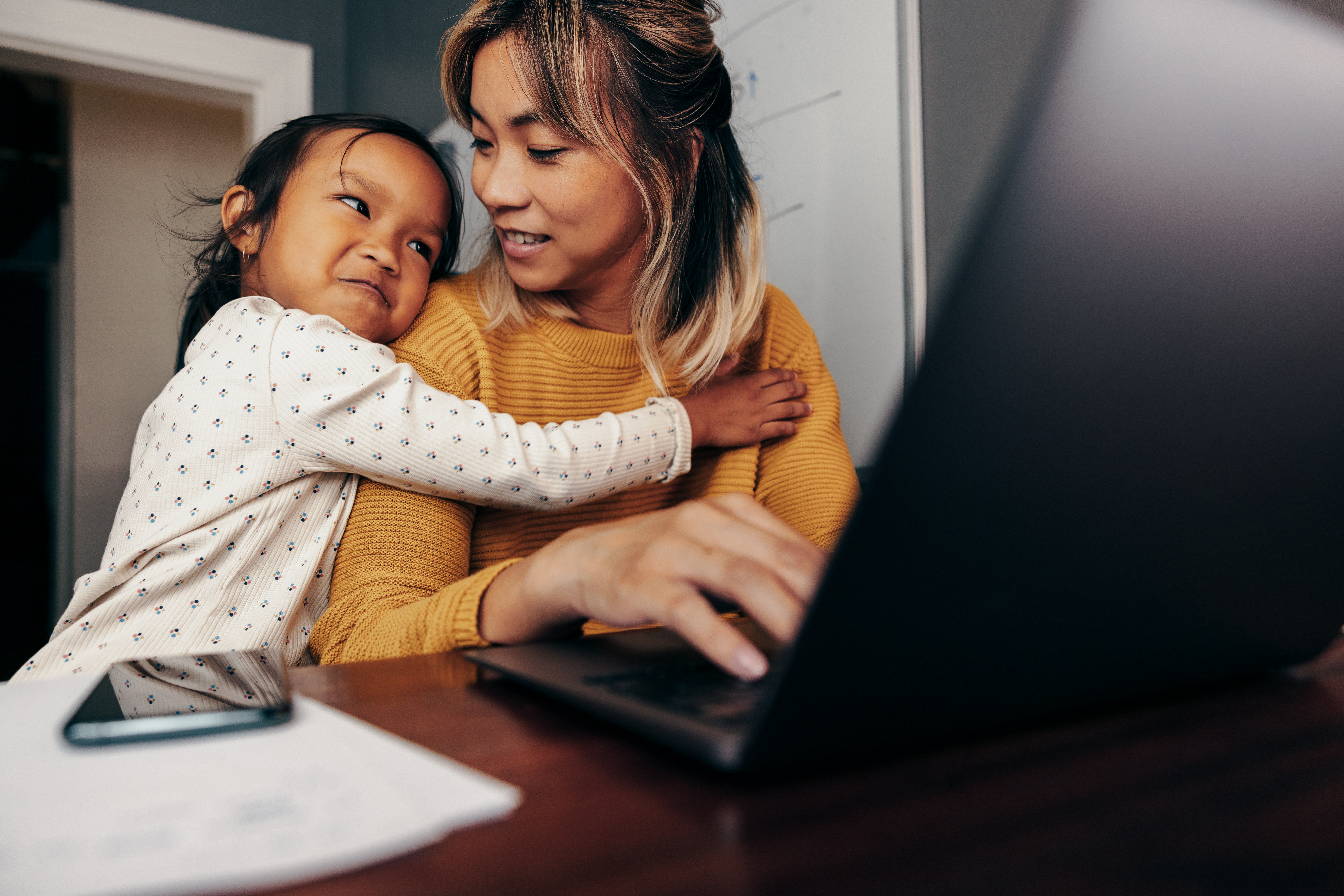 Woman and young child sitting together beside a laptop