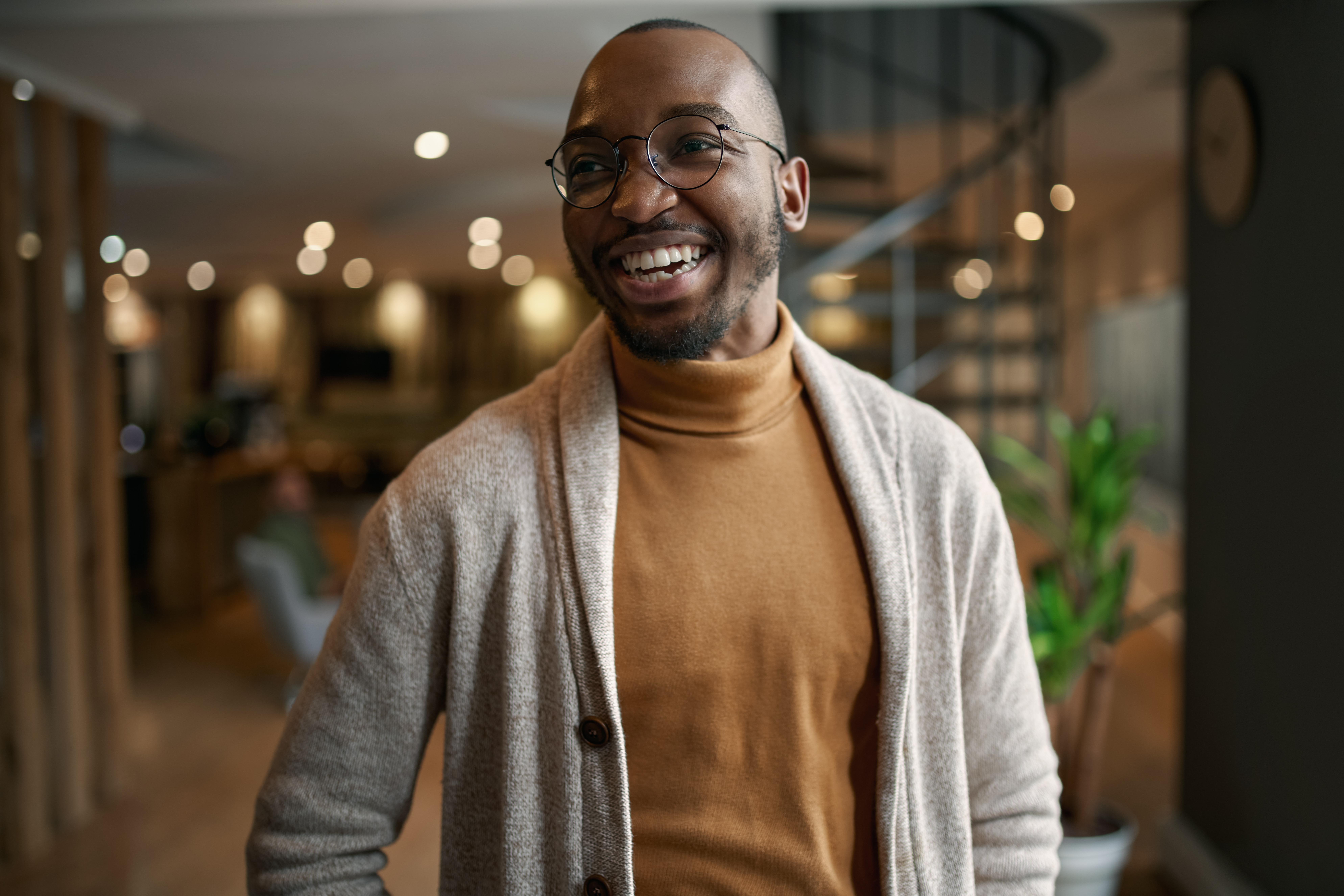 Smiling person wearing glasses and a cardigan
