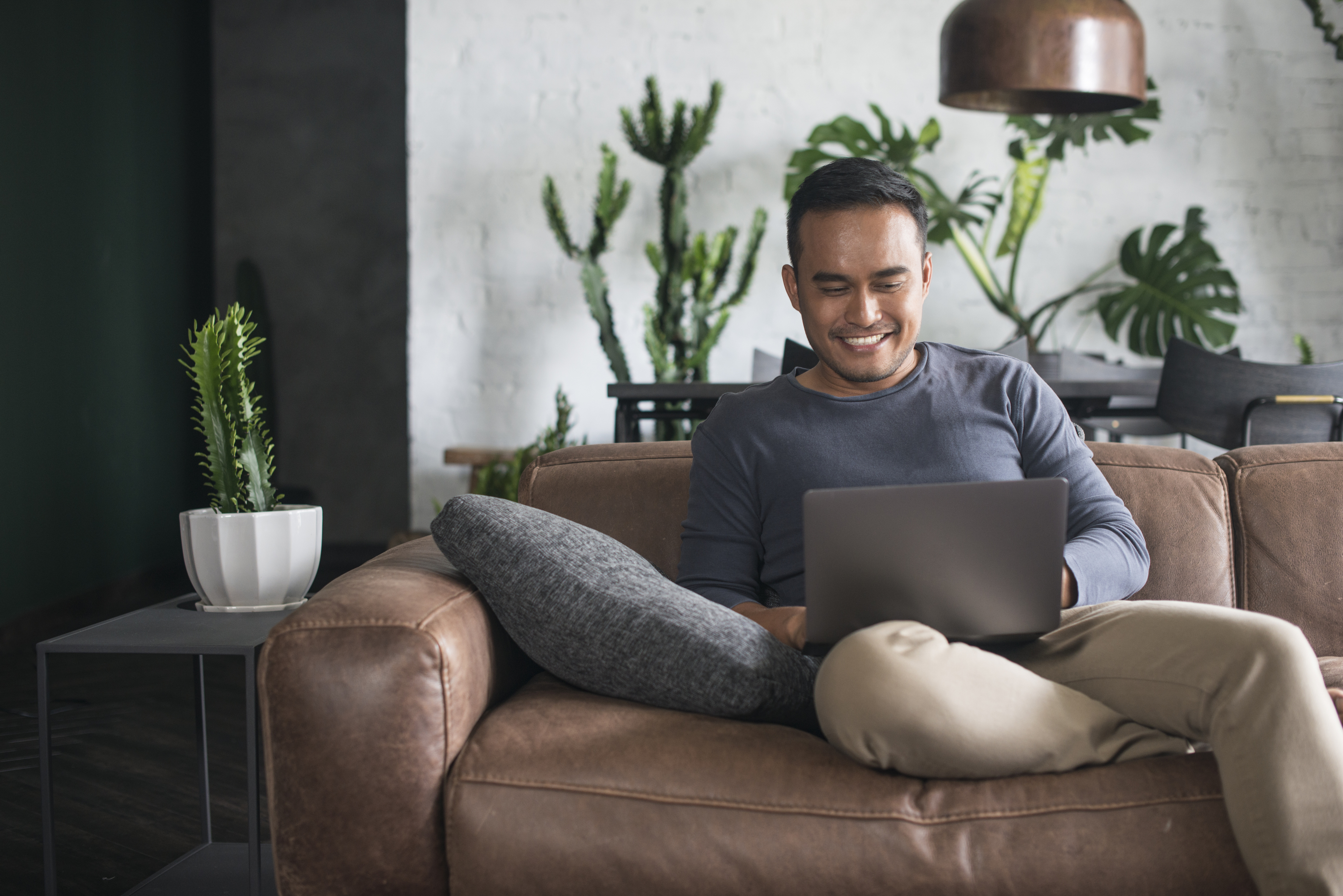 Person using a laptop while sitting on a sofa at home
