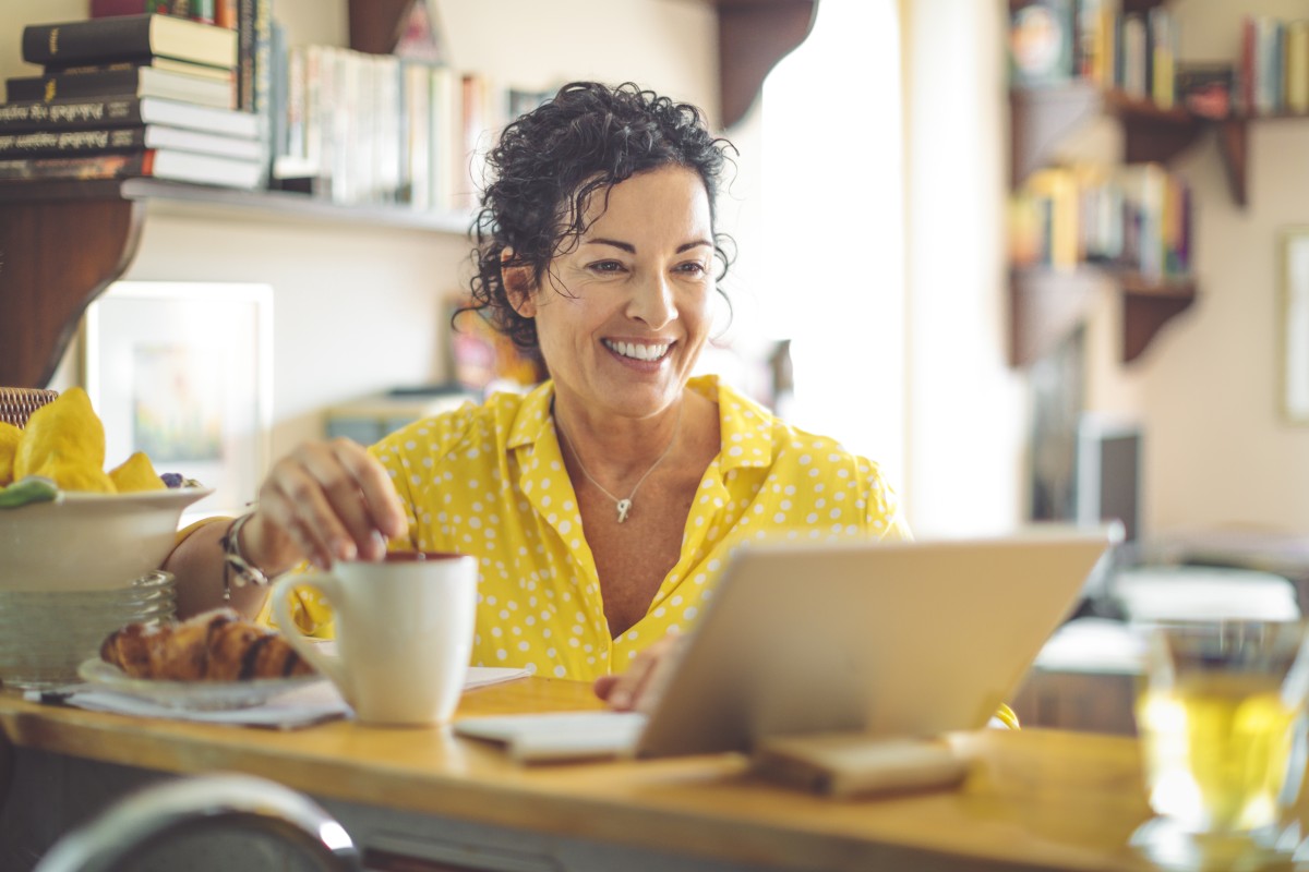 Woman smiling while using a tablet at a table