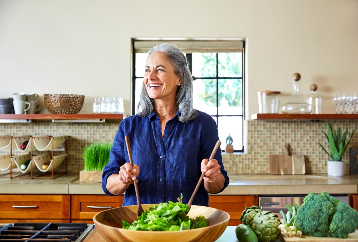 Woman smiling while preparing a salad in her kitchen